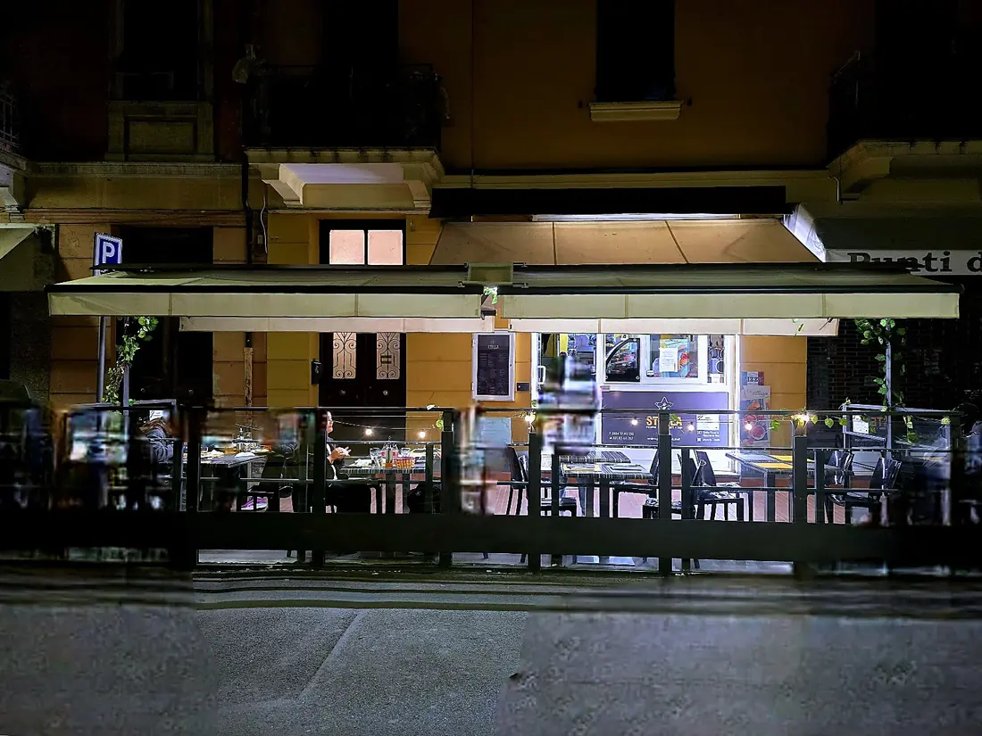 I tavoli di Stella all'aperto la sera, sotto la tenda, con il porta-menu Stella al muro